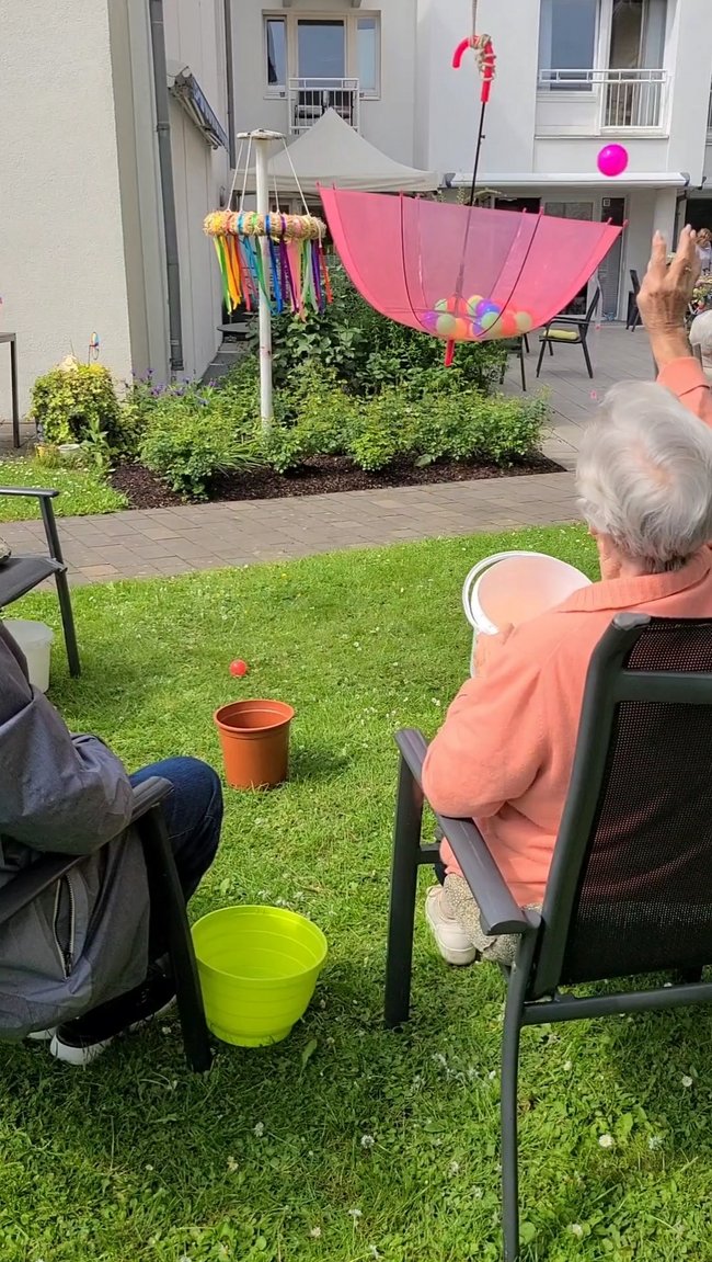 Bälle werden in den verkehrt herum aufgehängten Regenschirm geworfen.