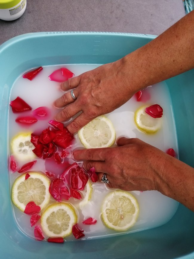 Handbad mit Milch, Rosenblättern und Zitronenscheiben.