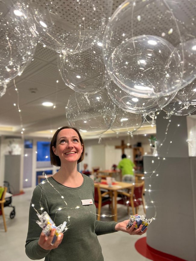 Annika Schneyder aus dem Sozialen Dienst hält lächelnd Lichterballons auf der Silvesterfeier.