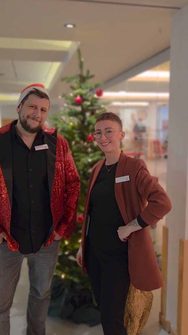 Lars Venne (Sozialer Dienst) und Birte Wind (Leitung Sozialer Dienst) stehen vor dem Weihnachtsbaum und freuen sich über die gelungene Weihnachtsfeier.