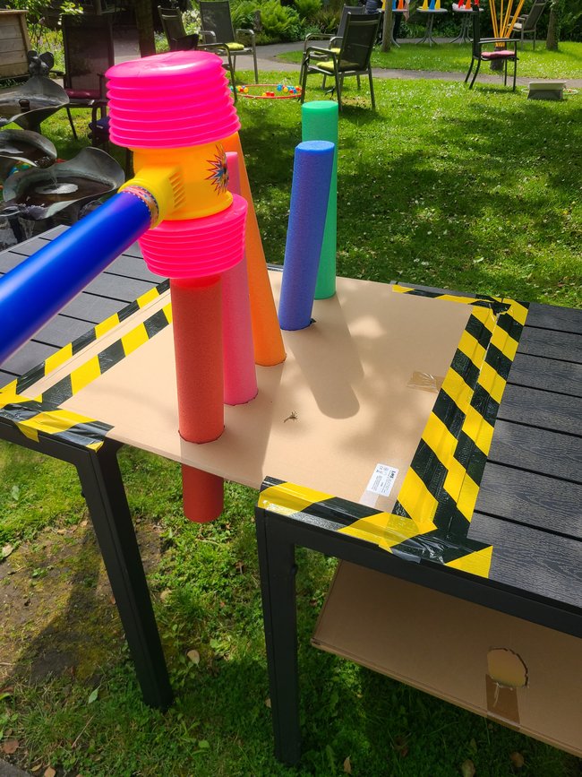 Beim Poolnudel-Hämmern wurden Poolnudeln mit einem Spielzeughammer durch Papplöcher gehämmert.
