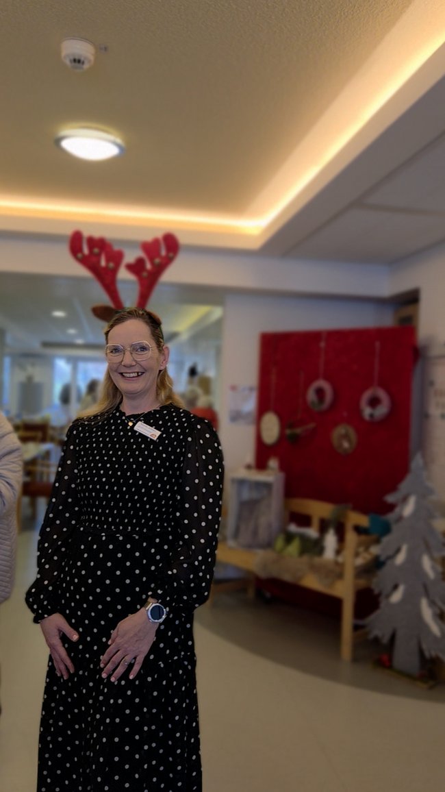 Eine Mitarbeiterin posiert mit Elchohren lächelnd vor der Kamera.