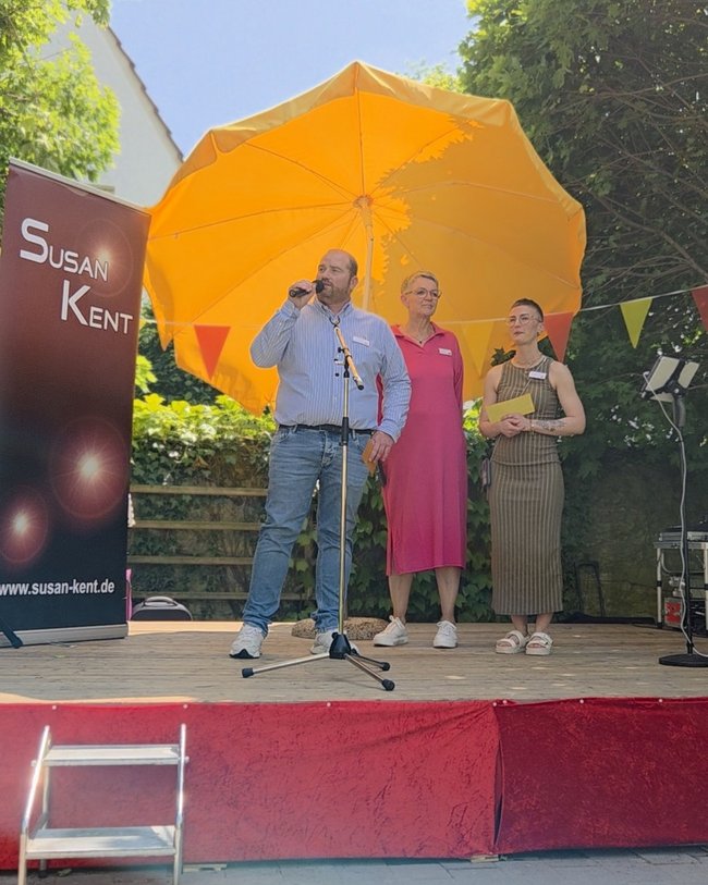 Begrüßung von Einrichtungsleiter Daniel Romberg, Sozialdienstleiterin Birte Wind und Seelsorgebeauftragte Elke Ruckebier auf der Bühne im Garten.