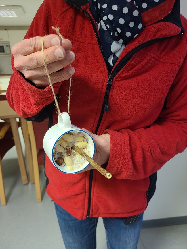 Vogelfutter in Tasse mit eingearbeitetem Ast zum Setzen für die Vögel.