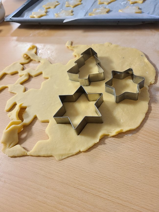 Weihnachtliche Plätzchen-Ausstecher liegen auf dem Teig.