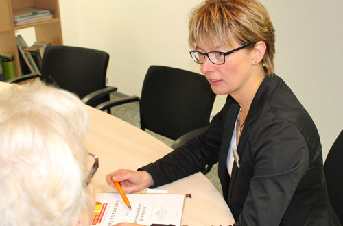 Eine Mitarbeiterin berät eine Seniorin über das Seniorencentrum.