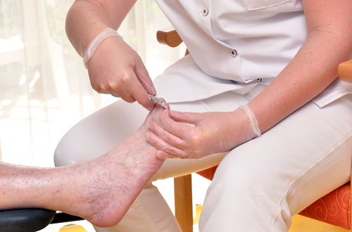 Die Fußpflegerin behandelt die Füße einer Bewohnerin.